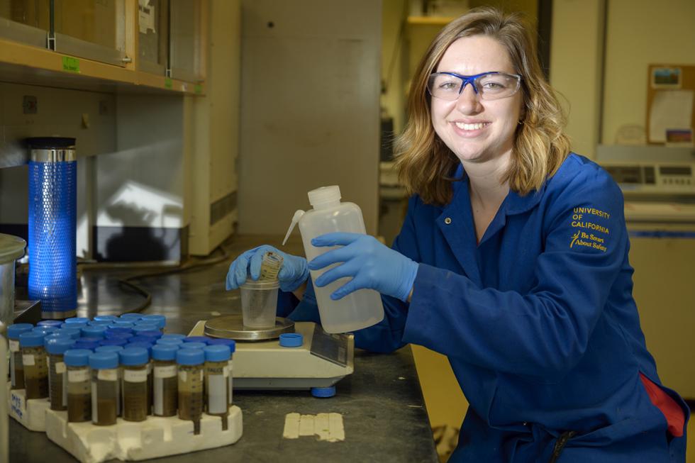 woman grad student in her lab and wearing blue lab coat 